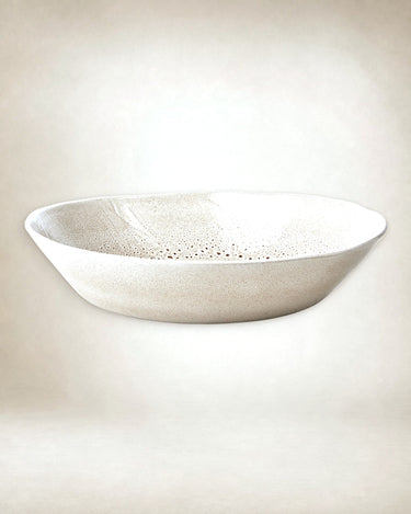 Ensaladera de cerámica esmaltada de Affari of Sweden: ensaladera beige de perfil bajo y moteado fino sobre fondo claro.