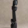Escultura Vical de teca negro mate sobre pared y suelo topo claro texturizado