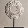 Figura Vical de piedra blanco roto y hierro negro sobre pared y suelo topo claro texturizado