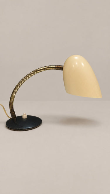 Brazo flexible curvado y pantalla inclinada hacia la mesa.
