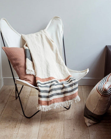 Fouta clara de lino con franjas sobre una butaca