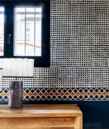 Friso Spotty Madagascar de papel de arroz en negro, ocre y crudo · 9 tiras de Le Monde Sauvage, colocado en una pared bajo una ventana