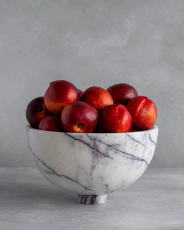 Frutero de mesa de mármol con pedestal de Kiwano Concept, blanco veteado, con fruta roja