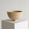 Frutero de piedra beige con base baja sobre un pedestal blanco