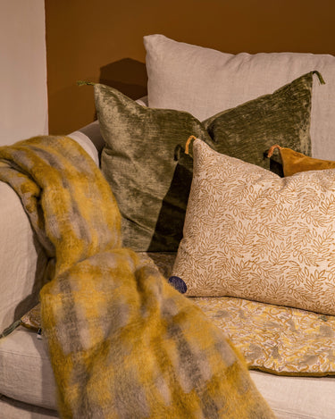 Cojín estampado ocre sobre una cama con textiles amarillos