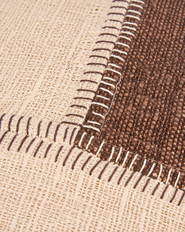 Funda de cojín patchwork de algodón marrón y natural, detalle de las puntadas entre los bloques marrón y natural