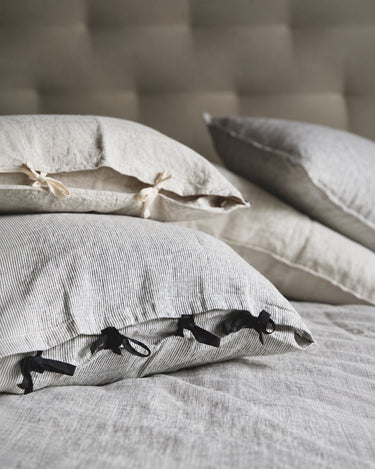 Fundas de almohada de rayas grises y lazos negros, detalle sobre la cama