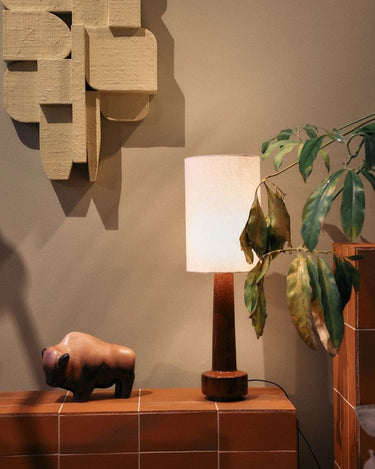 Pantalla de lino natural HK Living en ambiente, parcialmente cubierta por hojas
