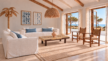 Salón junto al mar con mesa marrón de Roger Capron con azulejos botánicos, jarrón V.III de Marta Bonilla, cojines Lane azules y sofás blancos.