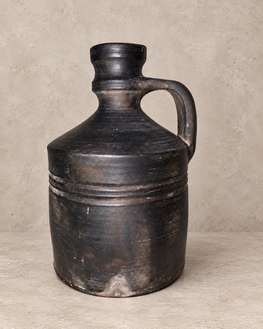 Jarra decorativa de cerámica negra asturiana, reverso con marcas de uso sobre cemento topo claro