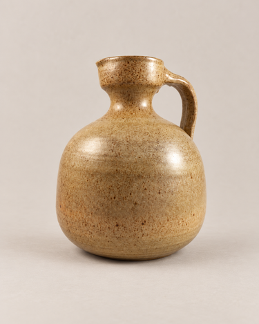 Jarra decorativa vintage de cerámica Enguita en tono ocre moteado, sobre fondo topo muy claro.