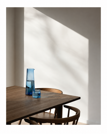 Jarra de vidrio azul de Bazar Bizar, sobre una mesa junto a vasos azules
