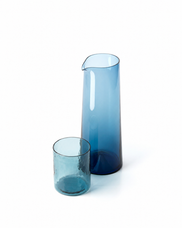 Jarra de vidrio azul, junto a un vaso bajo de vidrio azul martillado