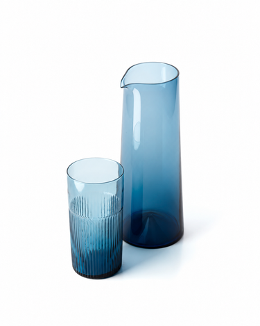 Jarra de vidrio azul, junto a un vaso alto de vidrio azul ondulado