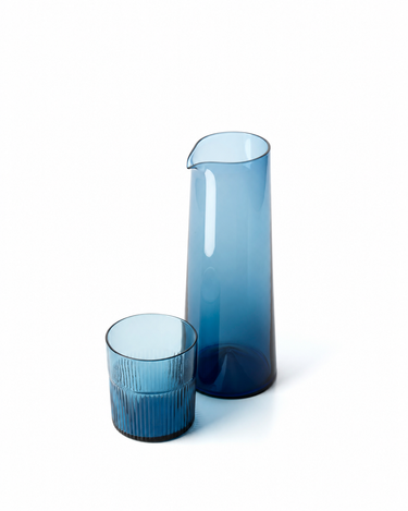 Jarra de vidrio azul, junto a un vaso bajo de vidrio azul ondulado