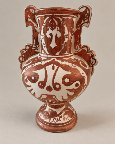 Jarrón cobrizo y crema con decoración vegetal, dos asas y pedestal.