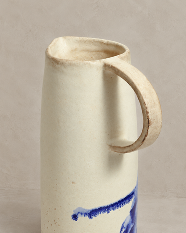 Detalle del asa y del borde del jarrón cerámico blanco con pinceladas azules