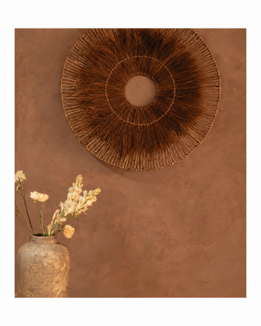 Jarrón de terracota en color crema, en una composición con una decoración circular de pared