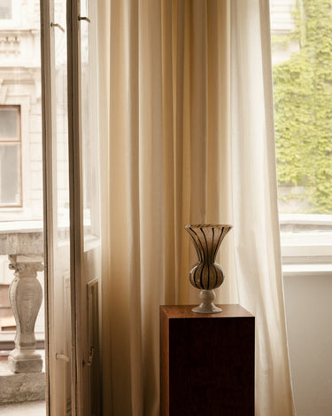 Jarrón Stria de Olsson & Jensen sobre un pedestal junto a una ventana