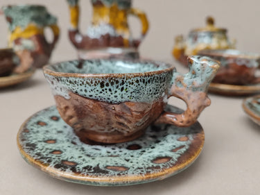 Detalle de una taza de cerámica moteada sobre su plato.