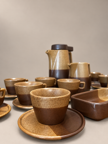 Juego de café vintage de gres beige y marrón: detalle de taza y plato con el conjunto al fondo sobre fondo topo claro