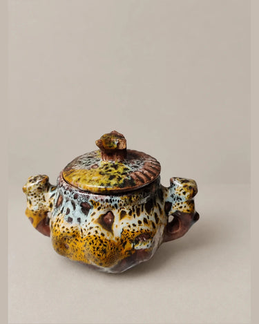 Azucarero moteado con tapa y pequeñas asas figurativas.