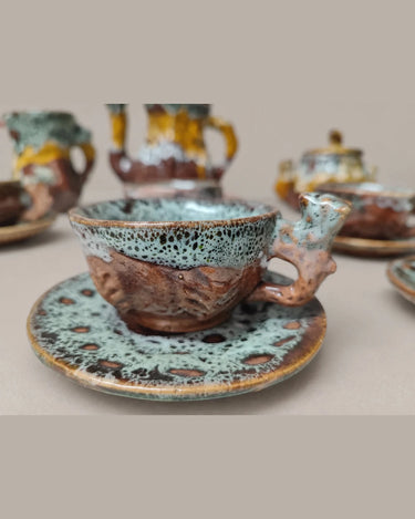 Detalle de una taza de cerámica moteada sobre su plato.