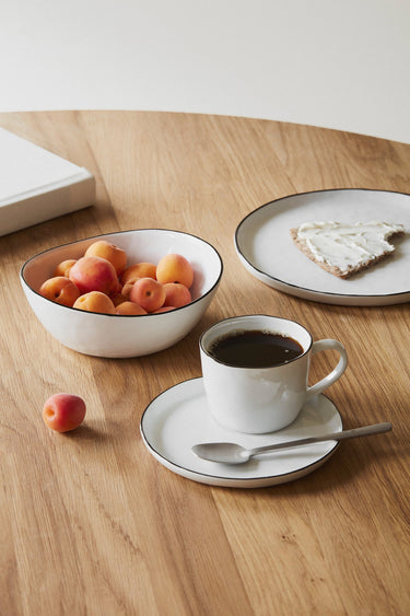 Juego de desayuno de porcelana blanca de Broste Copenhagen servido sobre una mesa de madera