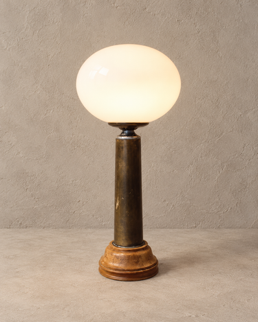 Lámpara vintage encendida vista desde arriba, con base circular de madera y globo de opalina