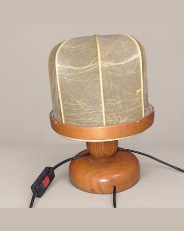 Lámpara de base de madera con pantalla segmentada y cable con interruptor rojo, vista en diagonal