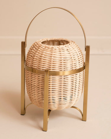 Lámpara de mesa inalámbrica de ratán con asa de Mahe Homeware: lámpara de ratán de cuerpo ovalado con asa, aro y patas de tono dorado.