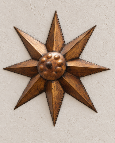 Lámpara sol vintage de metal dorado, con ocho puntas y centro en relieve, en primer plano