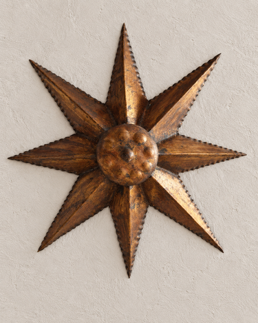 Lámpara solar vintage dorada vista de frente, con ocho rayos triangulares y centro circular abombado