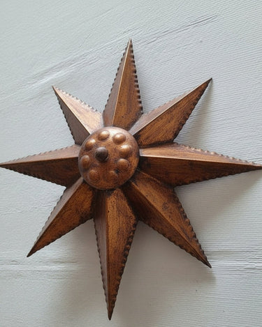 Lámpara sol vintage de metal dorado, con ocho puntas y centro en relieve, en primer plano