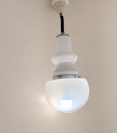 Lámpara de vidrio blanco encendida, con luz en el volumen inferior.