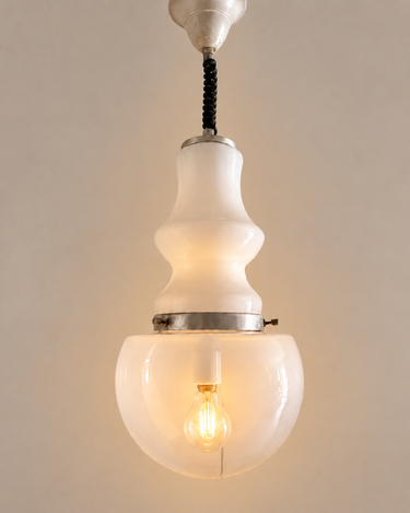 Lámpara de techo de vidrio blanco con aro plateado y bombilla convencional encendida con luz cálida.