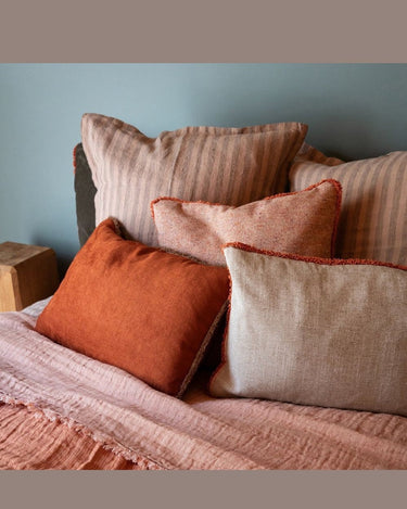 Square cushion with natural-toned fringe, on a sofa by Le Monde Sauvage