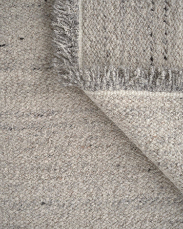 Detalle de la alfombra Peaceful Parity de lana y yute en tono mármol