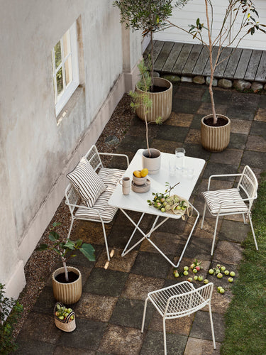 Maceta cilíndrica beige con planta en una terraza