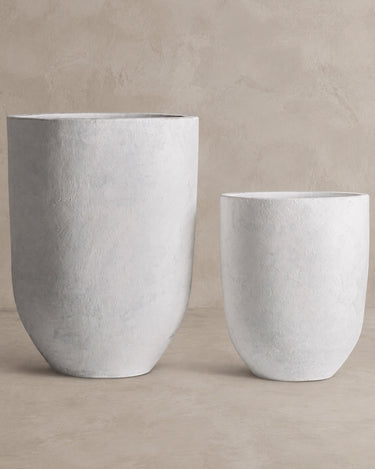 Juego de dos maceteros Vical de terracota blanco roto sobre pared y suelo topo claro texturizado