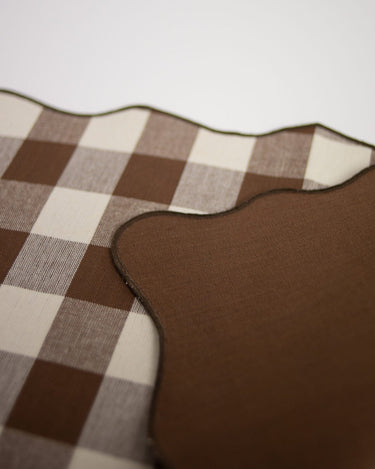 Cara de cuadros y reverso liso marrón de los manteles individuales reversibles