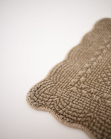 Detalle del borde ondulado y la textura del mantel individual Delphine topo de Olsson & Jensen
