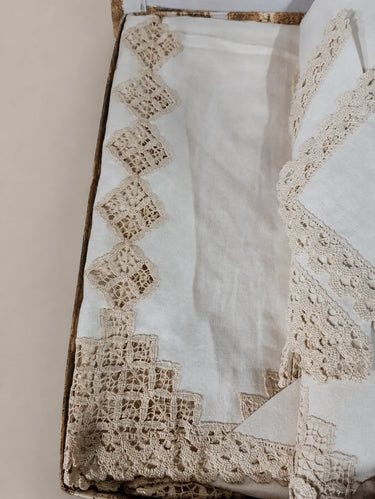 Detalle del borde festoneado y el calado beige sobre tejido crudo.