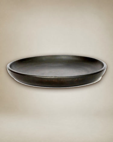Small black ceramic plate by Bazar Bizar on a table