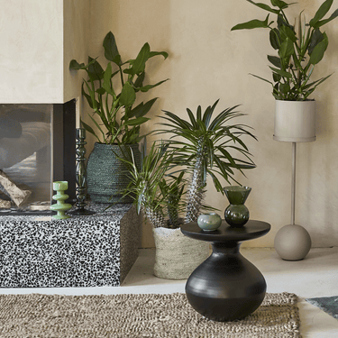 Mesa auxiliar de aluminio negro: en un rincón verde con plantas y piedra