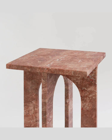 Mesa auxiliar Bond de piedra natural de Kiwano Concept, en tono rojizo, detalle del tablero y el arco