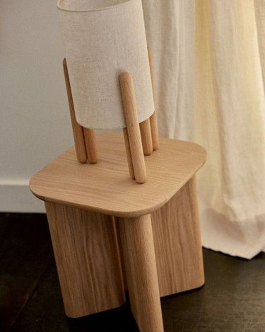 Mesa auxiliar Gabrielle Paris de fresno natural con una lámpara sobre el tablero