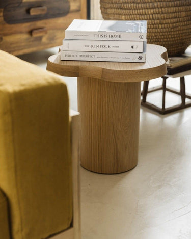 Mesa auxiliar de fresno natural con libros apilados sobre el tablero