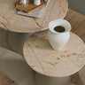 Mesa auxiliar de mármol beige junto a un sofá