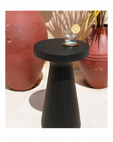 Mesa auxiliar negra de madera de suar de Bazar Bizar, con un vaso sobre el tablero